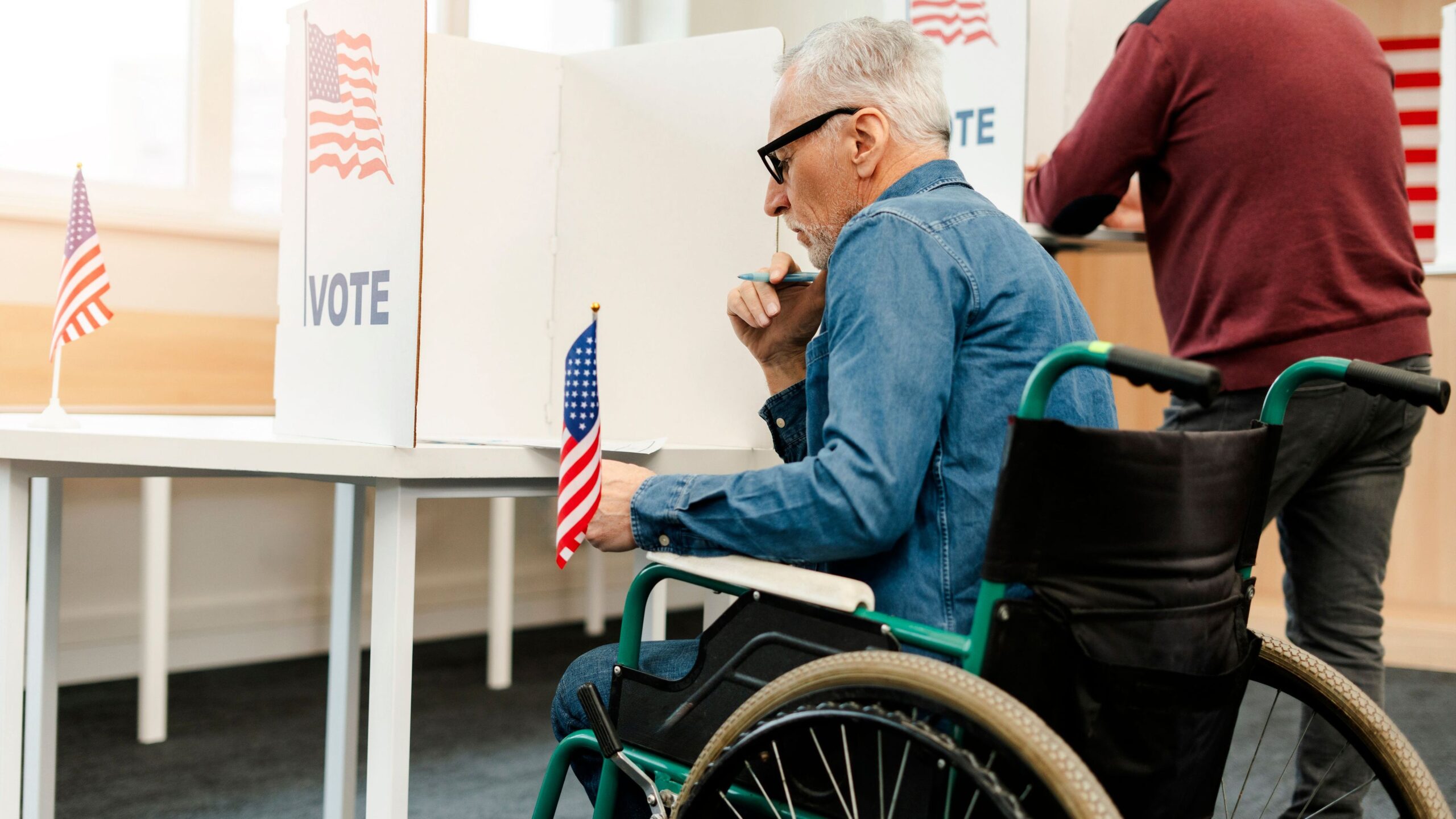 A man in a wheelchair casts his votes at a polling place.